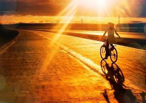 oloi-oi-dromoi-ingolden.gr-woman-bicycle-sunrise-summer-gold-orange-street-way
